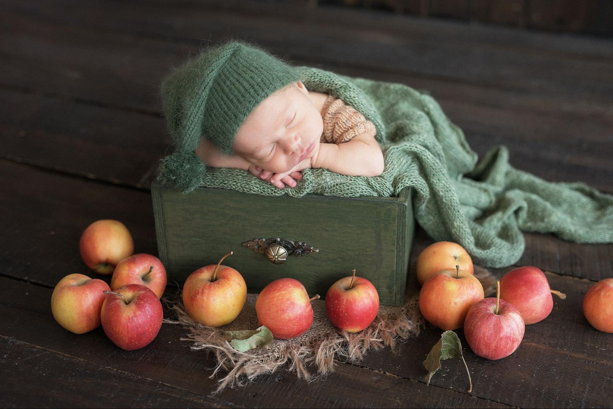 Baby in fruit stand, surrounded by colorful fruits, capturing sweetness and freshness