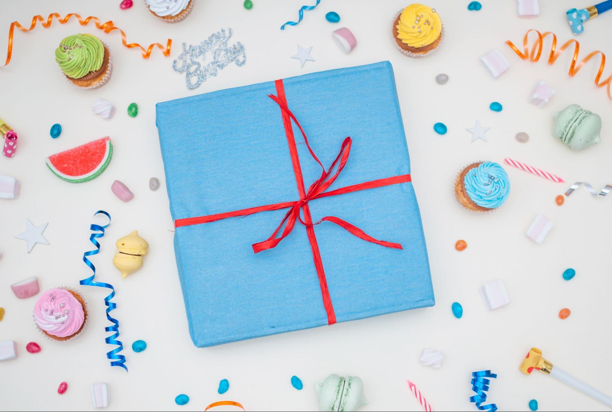 A personalized Puzzle Birthday Gift: a vibrant blue gift box amidst a shower of confetti and colorful confetti