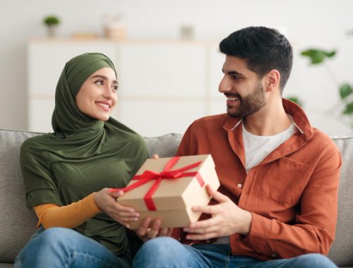 A joyful Muslim couple exchanging birthday gifts on their special day