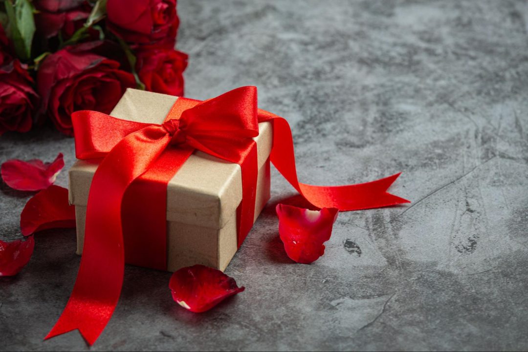 Elegant Wedding gift box with red ribbon and roses on table