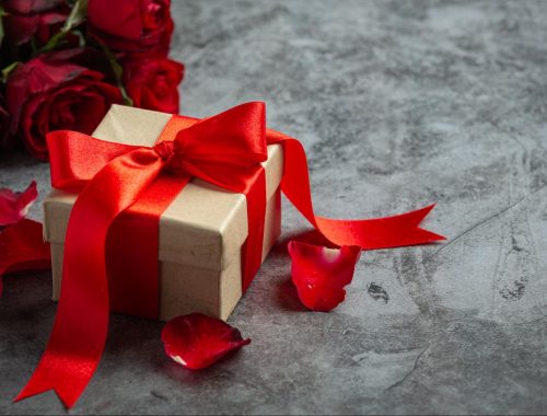 Elegant Wedding gift box with red ribbon and roses on table