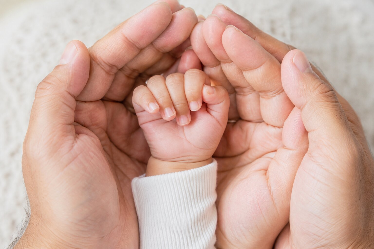 Parent holding baby's tiny hand during a close-up photoshoot
